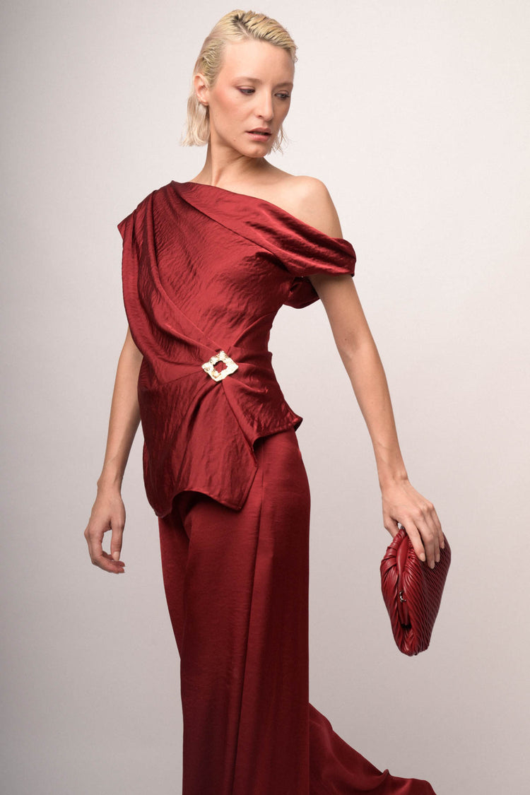 Top asimmetrico in raso bordeaux con spilla gioiello