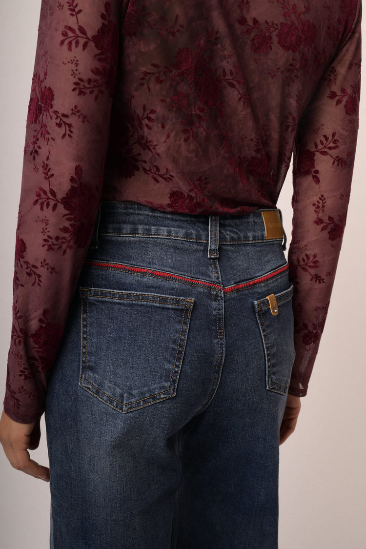 Jeans in denim blu a gamba svasata con impuntura rossa