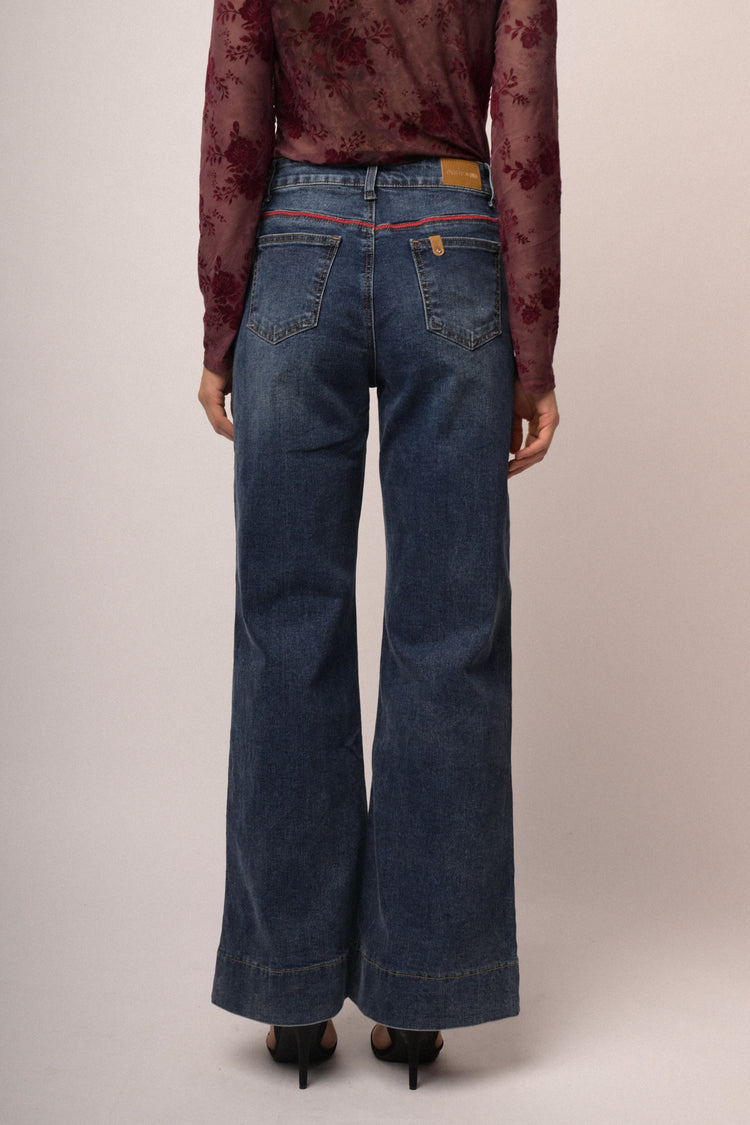 Jeans in denim blu a gamba svasata con impuntura rossa