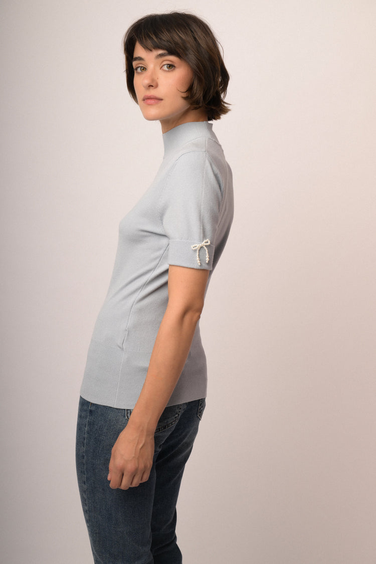 Lupetto in maglia celeste con fiocchetti decorativi alle mezze maniche