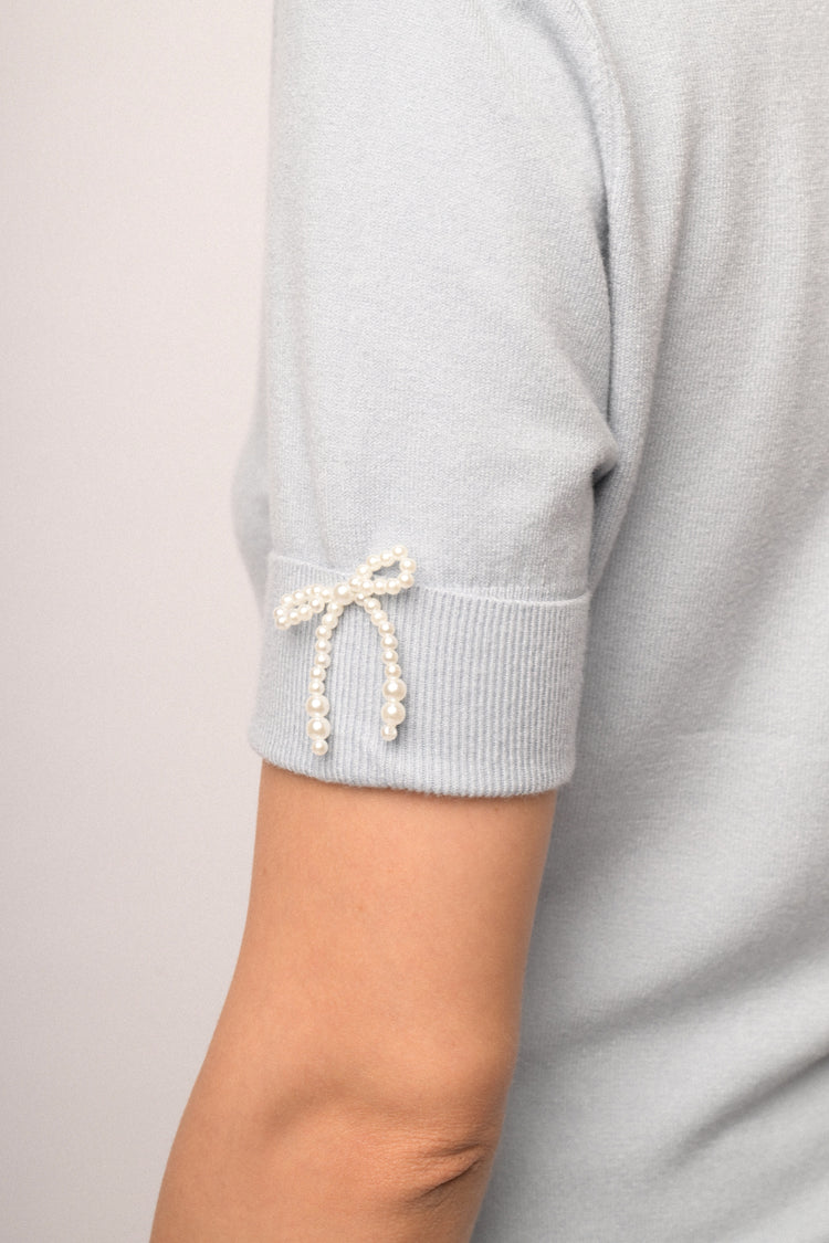 Lupetto in maglia celeste con fiocchetti decorativi alle mezze maniche