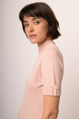 Lupetto in maglia rosa con fiocchetti decorativi alle mezze maniche